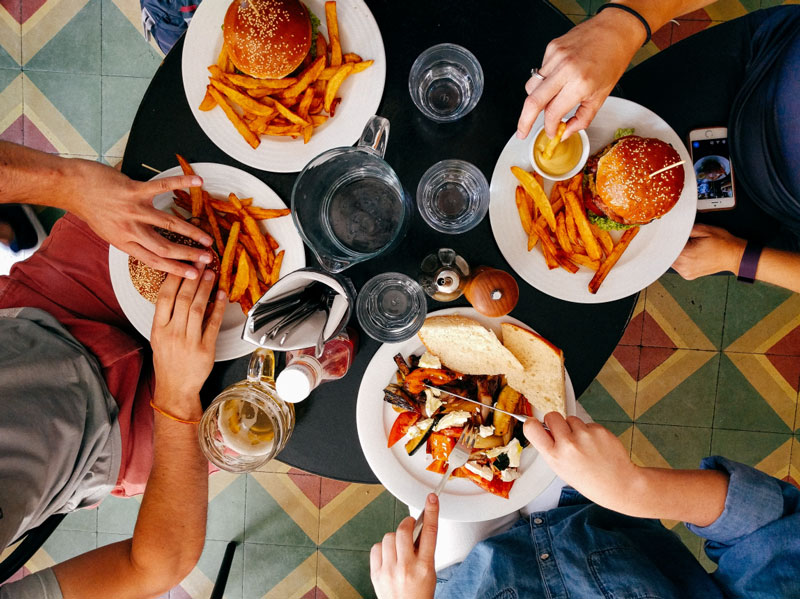 Photo of hands eating burgers and fries