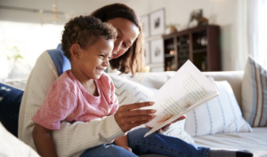 Black mother reading to her young Black child
