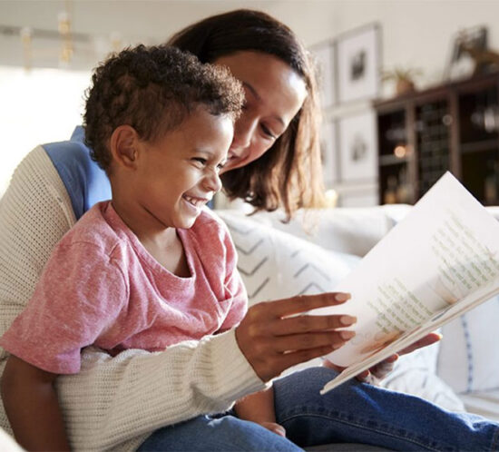 Black mother reading a book to her Black daughter